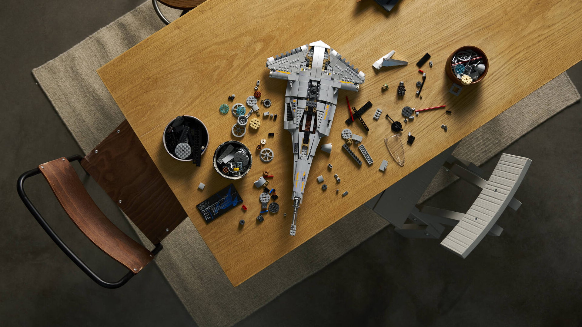 A partially-built Lego N1 Starfighter in pieces on a wooden table