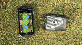 A GPS device and laser rangefinder pictured next to each other on grass