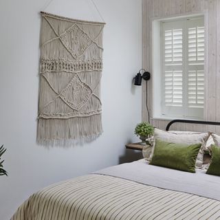 bedroom with double bed, hanging wall tapestry and window shutters