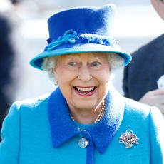 Queen Elizabeth wears a blue and turquoise coat with a matching hat