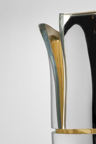 Detail of a Silver mirrored vase with a cut at the front showing a golden inside.