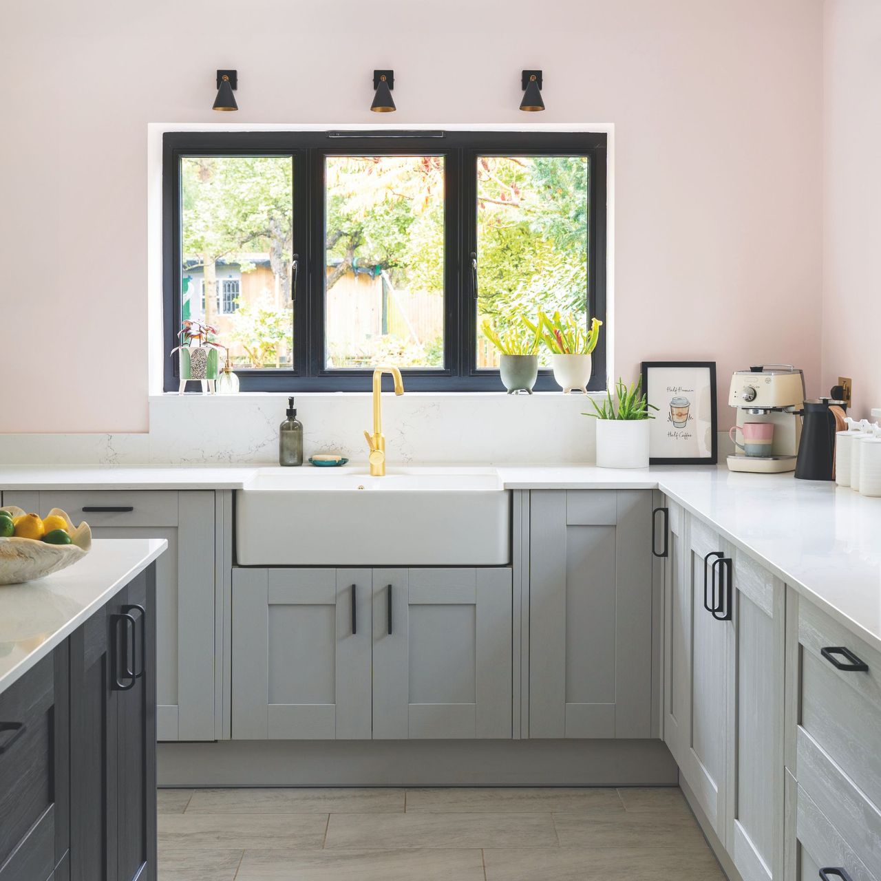 Pink painted kitchen with grey cabinets and a white worktop