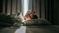 A woman lies in bed looking tired and sick