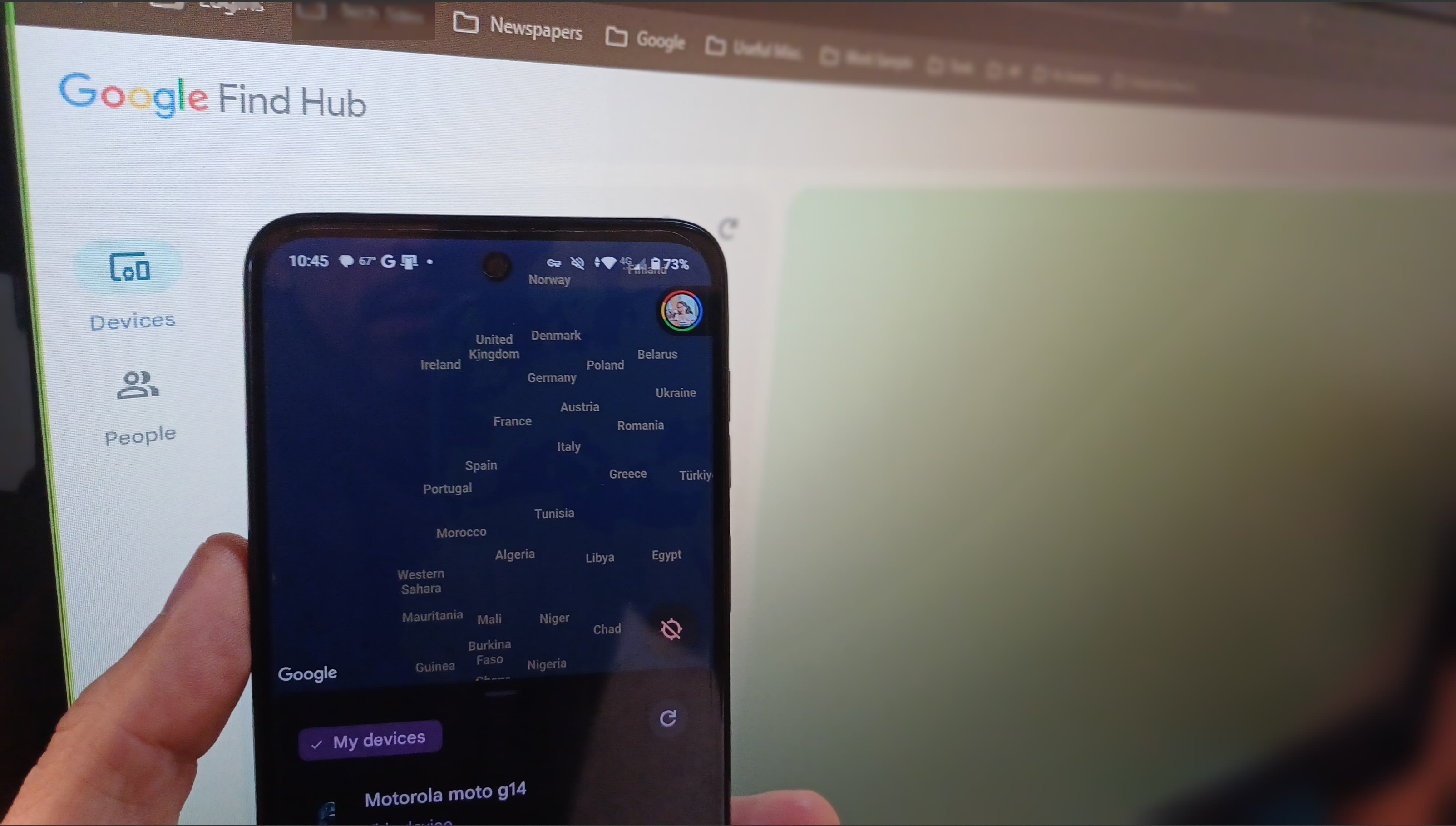 Android phone against monitor with Find Hub on the screen