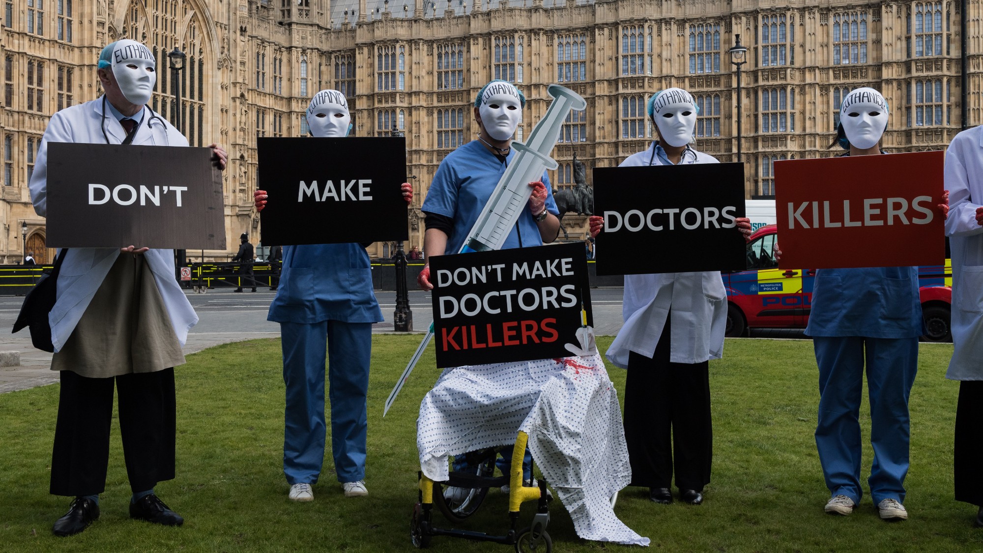 Pro-life campaigners dressed as masked doctors protest outside Parliament against assisted dying