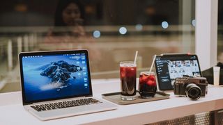 a laptop and an iPad on a table with drinks between them