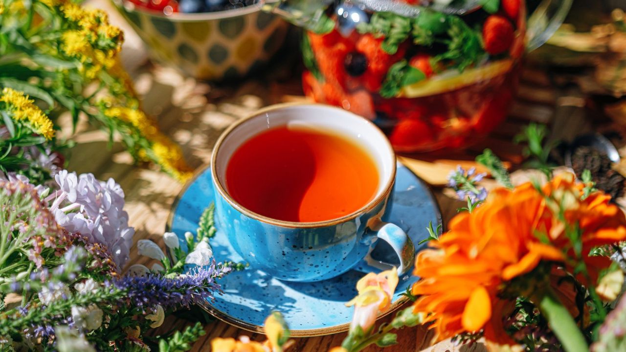 Tea in a blue teacup and saucer surrounded by flowers