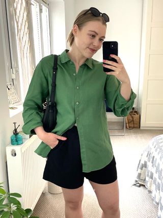 Woman in green shirt, black shorts, sunglasses, handbag