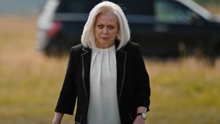 Jacki Weaver as Caroline in Yellowstone walking through a field and talking.