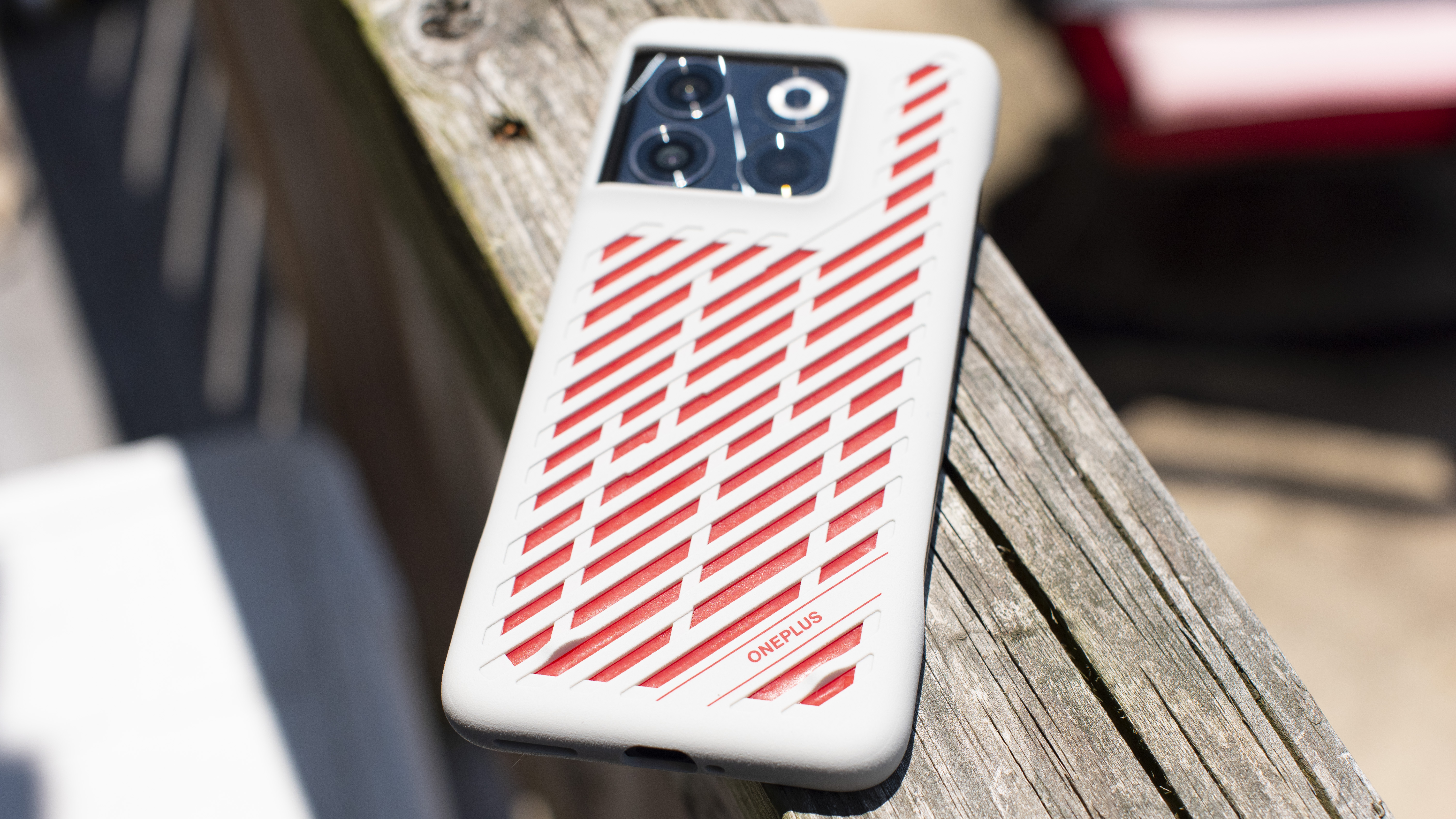 OnePlus 10T in a glacier mat case with red stripes on a wooden beam