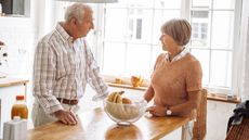 A retired couple have a serious conversation at the island in their kitchen.