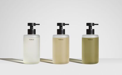 Three Forgo hand wash bottles in refillable containers against grey background