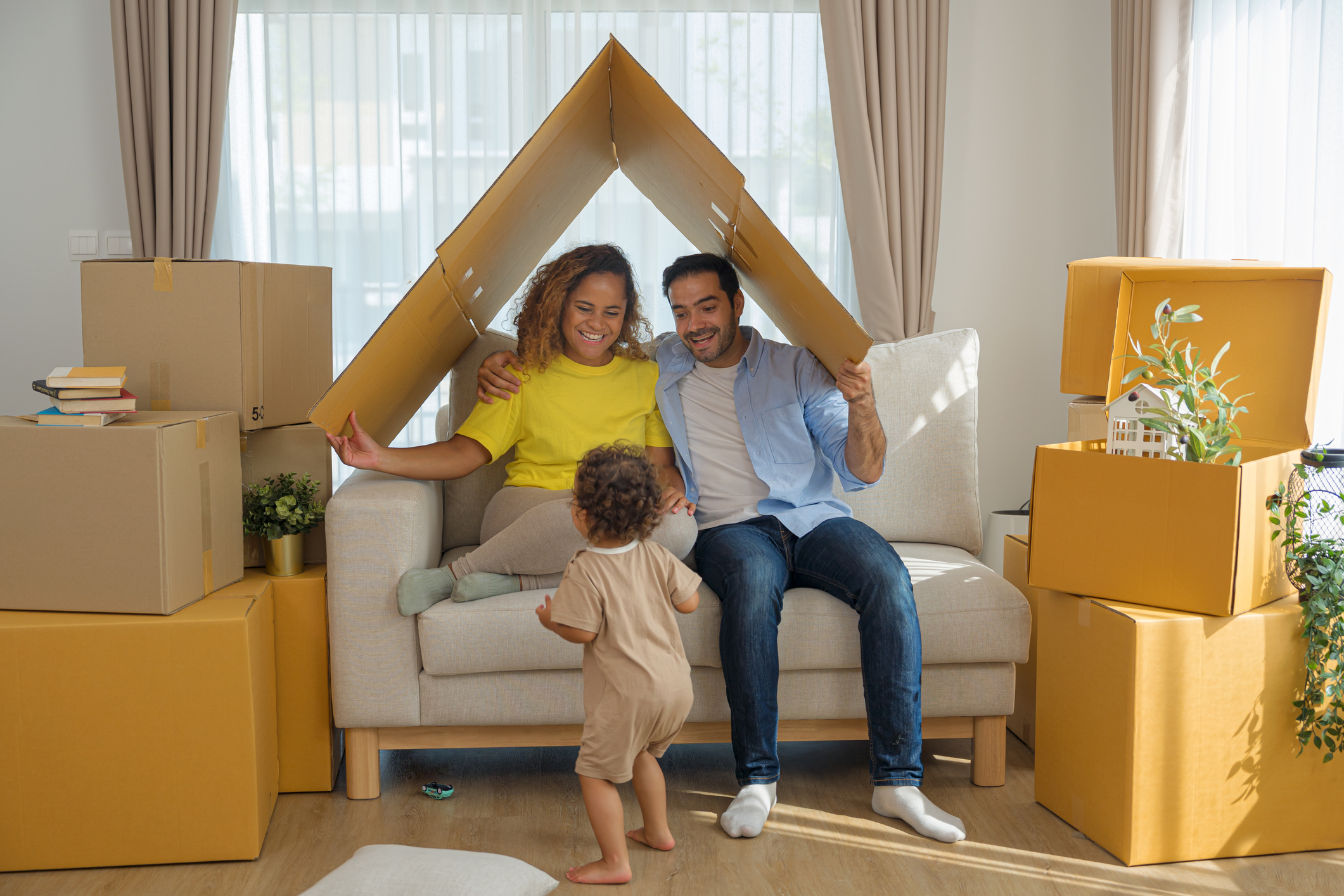 A young couple with a toddler playing in a house they've recently moved into.