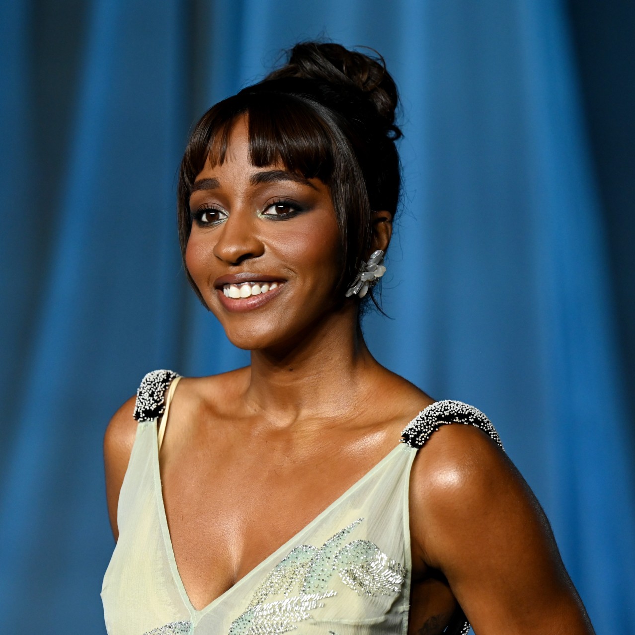 a black woman with dark hair posing on a red carpet in front of a blue background