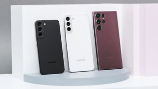 Samsung Galaxy S22-serien står uppställda bredvid varandra i färgerna vitt, svart och rött, med baksidorna vända mot kameran.