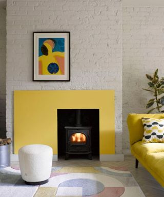 living room with white brick wall, yellow couch and log burner with yellow accent wall surrounding it