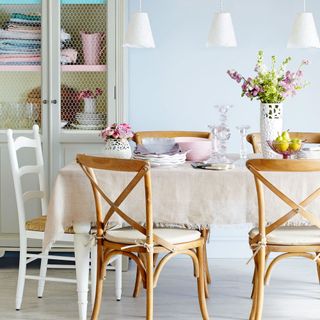 Dining room with pastel blue walls, wooden table and chairs and white hanging pendant lights