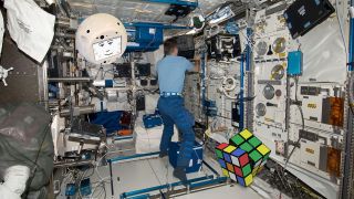 CIMON is pictured here, flying around in zero gravity with a human colleague and a Rubik's cube.