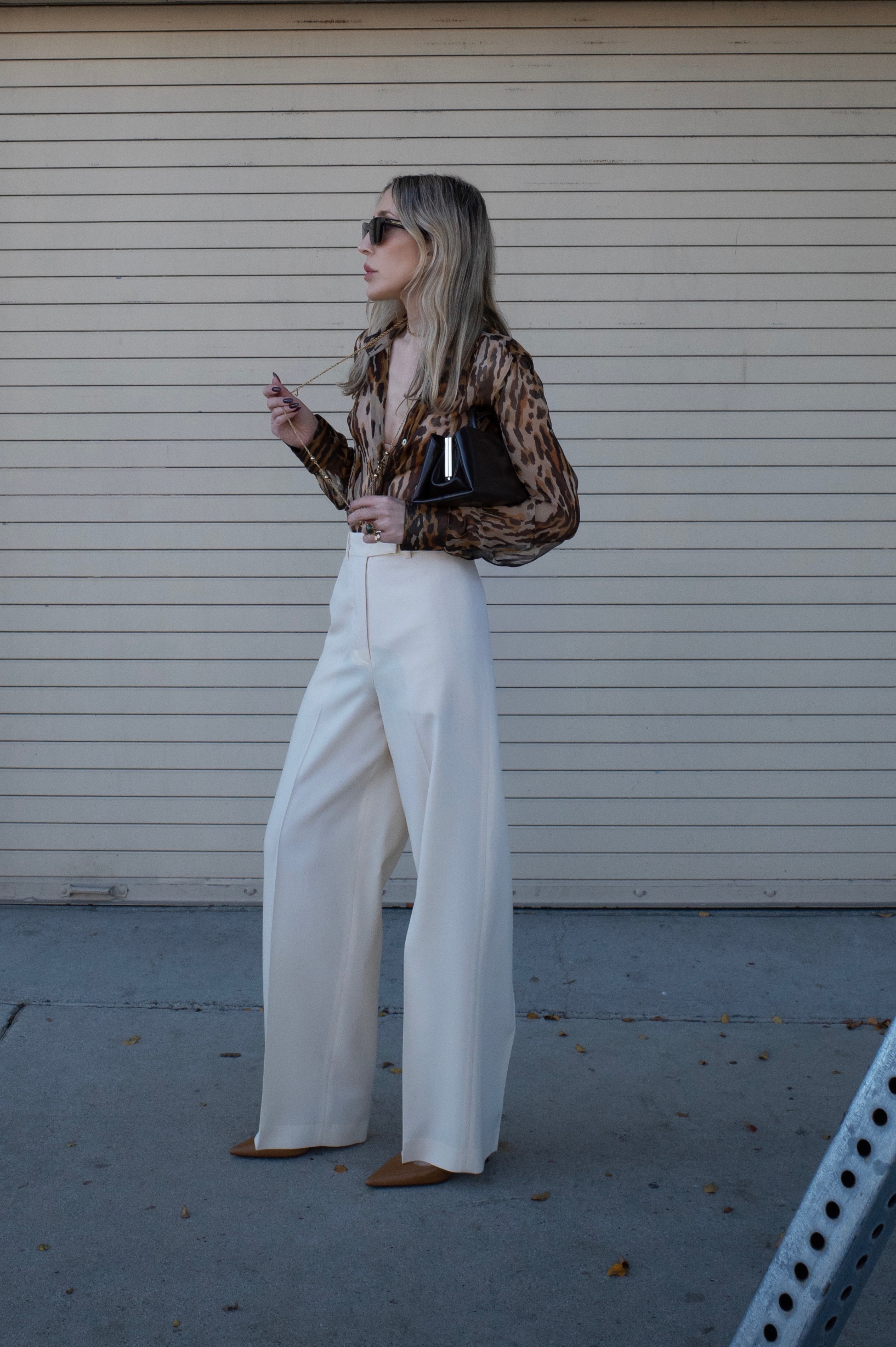 Angela Fink wearing a cheetah print top, white pants, and heels