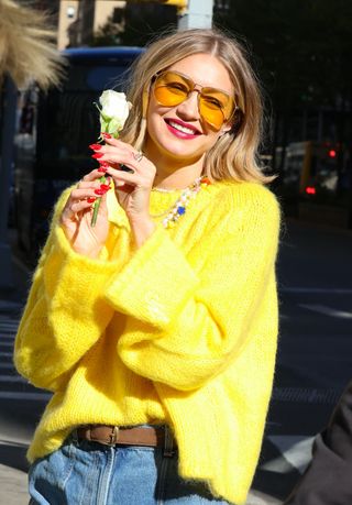 A photo of Gigi Hadid matching her red nails to her reddish pink lipstick.