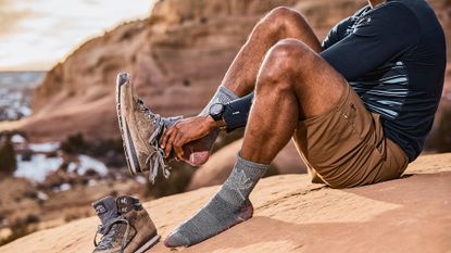 Best hiking socks: Man putting his foot into boot wearing Smartwool Hiking Socks