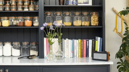 black wooden shelving with tongue and groove and lots of cook books and kilner jars