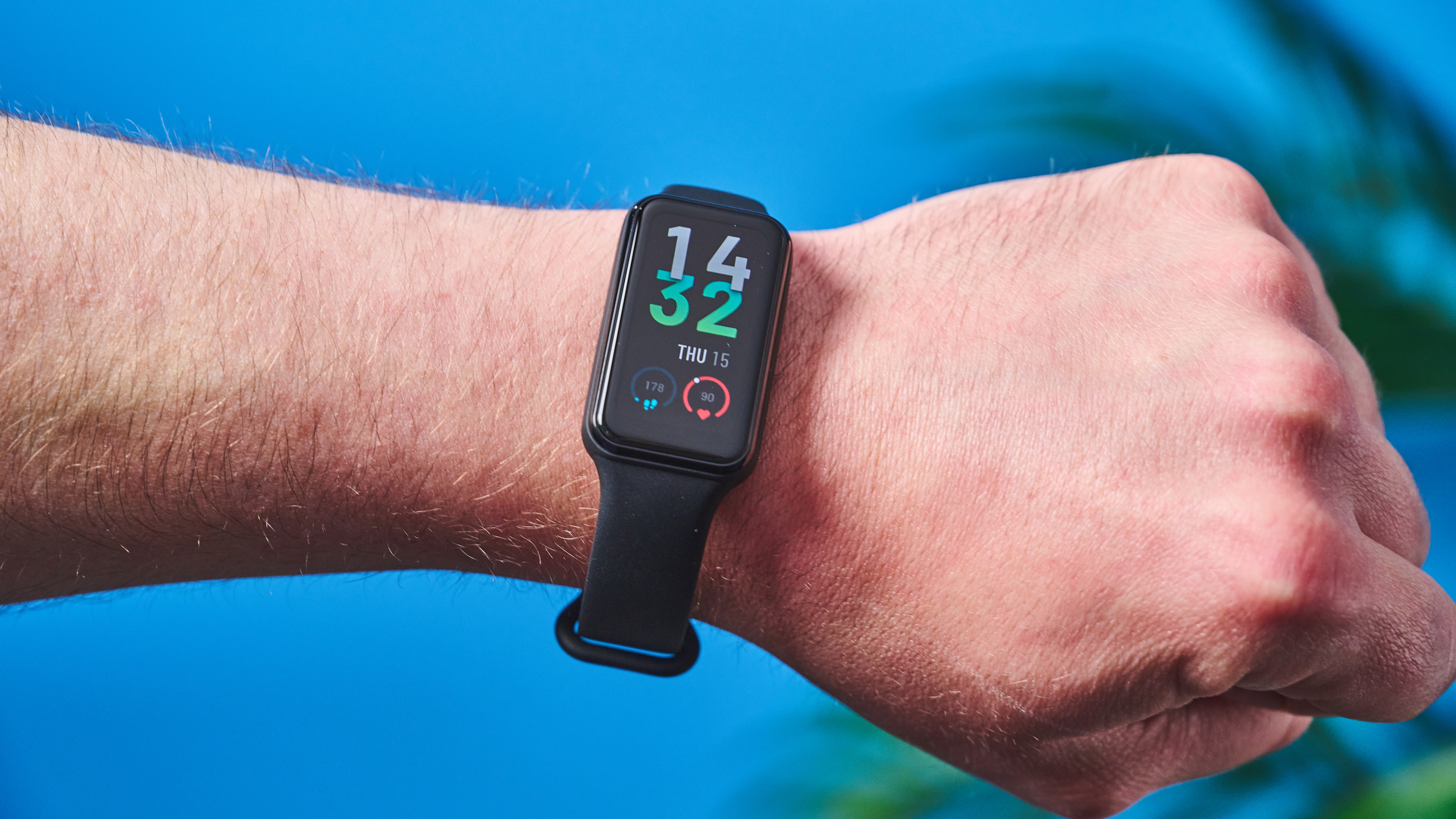 a small fitness tracker with a smooth touchscreen and TPU strap and a bright, vibrant screen showing activity types and a heart rate monitor on the underside