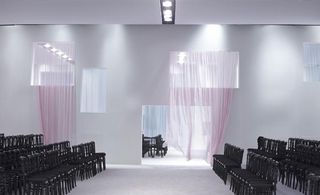 White room, with light pink curtains and black chairs