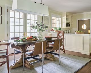 neutral kitchen diner with off white cabinets, wooden table with metal top and gray rug
