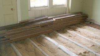 Floorboards lifted in a room with insulation in the floor