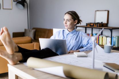 Woman in office working on laptop with feet on table, benefits of working from home