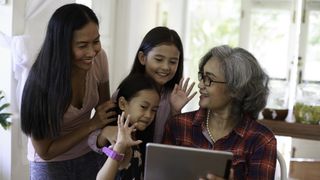 Three generations of women - a grandmother, mother, and two young faughter - looking at smart tablet