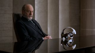 Wade (Liam Cunningham) sits at a desk with a helmet on it in 3 Body Problem episode 4