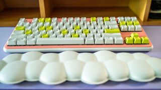 Logitech G715 TKL in its pink deck cover and white and green keys on purple Logitech desk mat