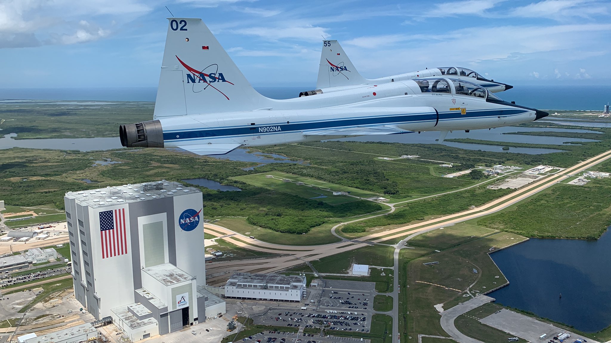 A pair of NASA T-38 jets fly past launch complex 39B at Kennedy Space Center.