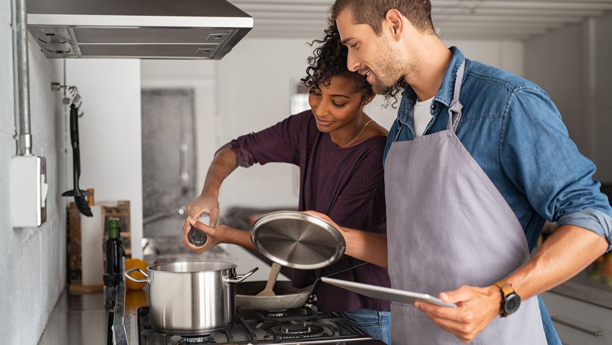 Man and woman cooking, following recipe on tablet