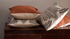 throw cushion set with mixed orange, natural, and patterned designs on top of a timber box