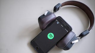 Spotify app on phone wrapped in headphones on gray background