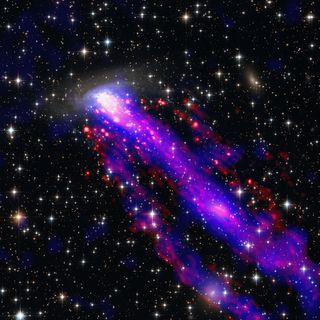 Against a dark background of space speckled with bright dots of stars and galaxies, a streak of bright purple is seen going diagonally from the bottom right of the image toward the top left.