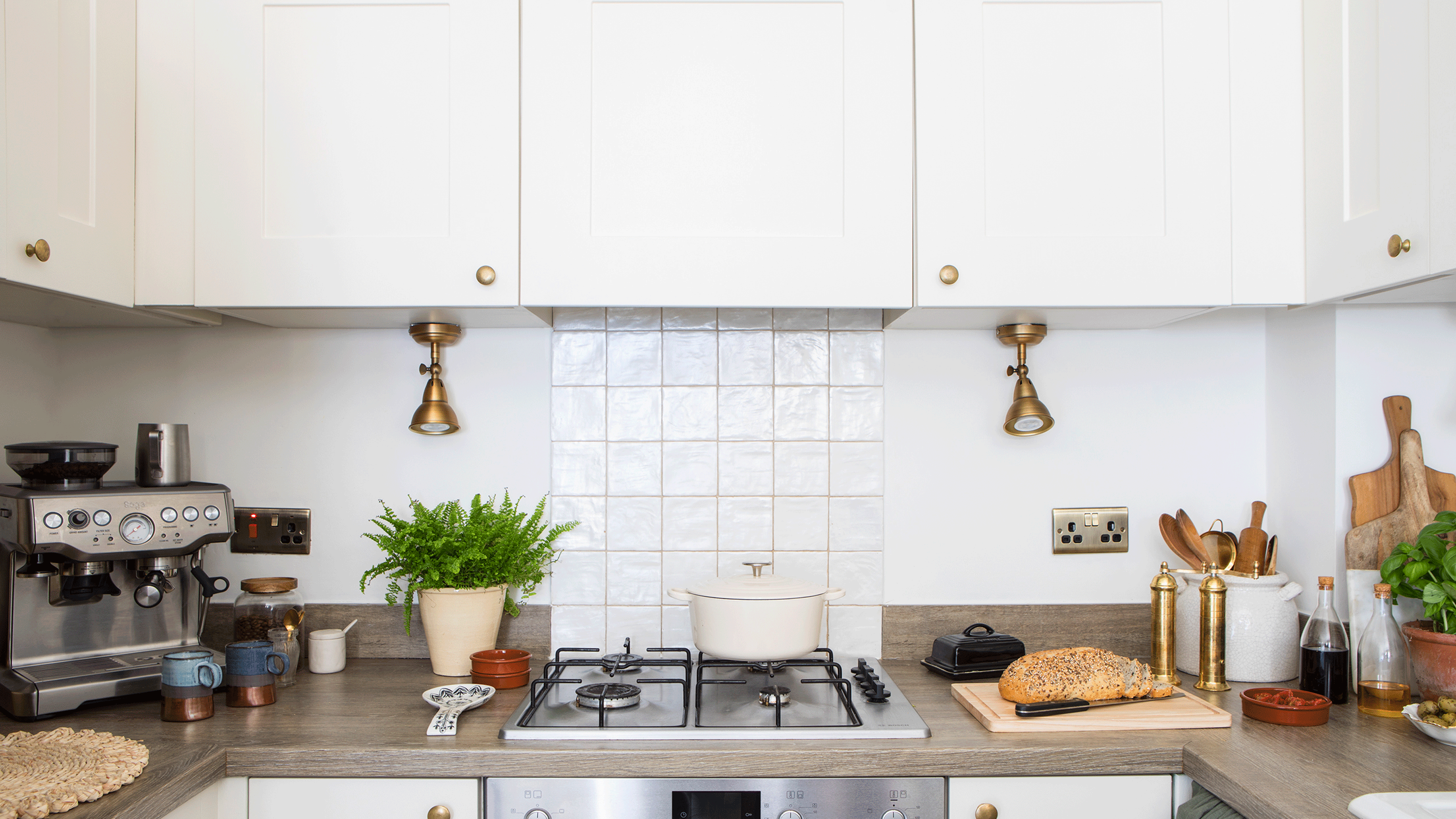 White kitchen with white walls and kitchen counter top with coffee machine, butter dish and plants