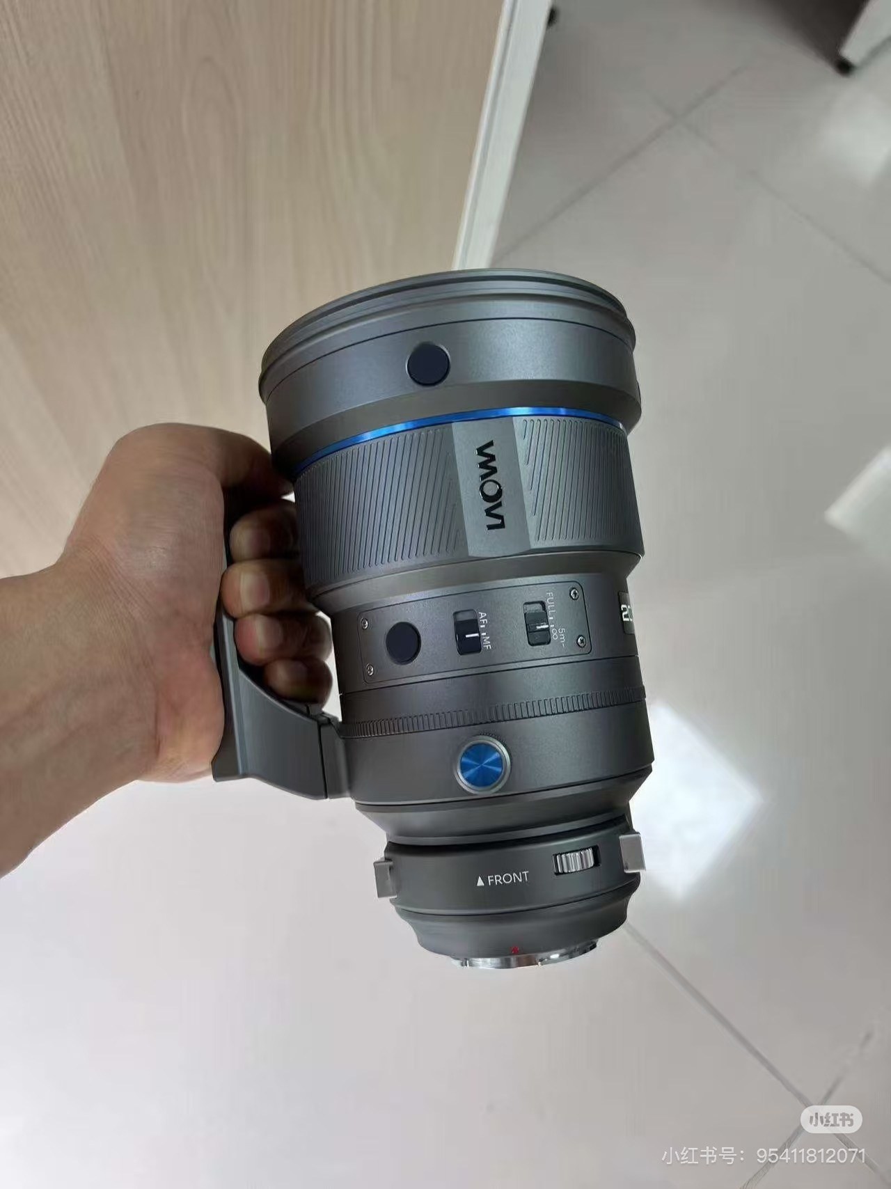 A hand holding the Laowa AF 200mm f/2.0