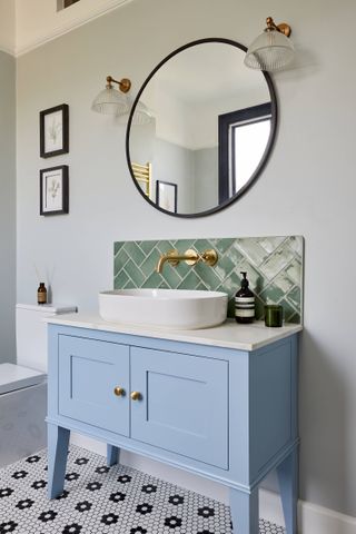 blue bathroom vanity unit with green splashback tiles and white sink