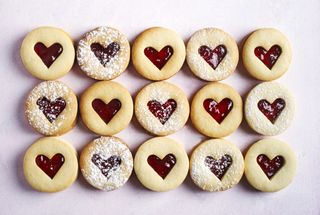 Round shortbread biscuits with heart cut outs and jam.