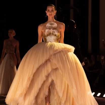a model wears a dramatic gown at the schiaparelli ss26 show