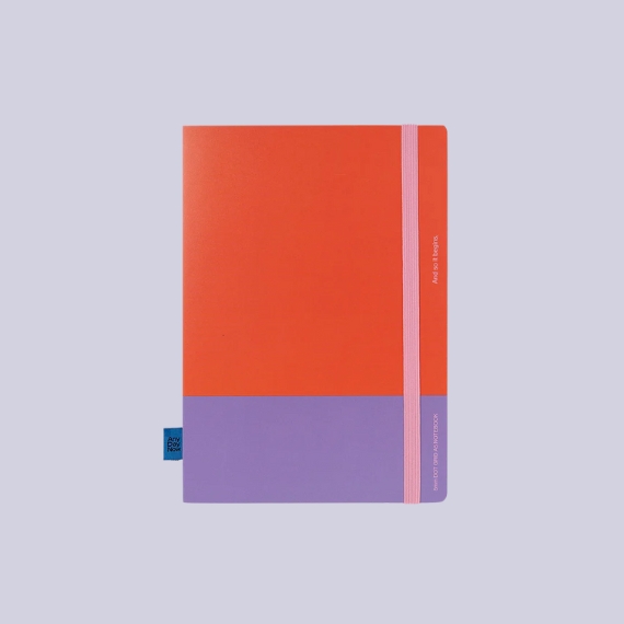 A lilac, pink, and red color-blocked notebook sitting against a lavender purple background.