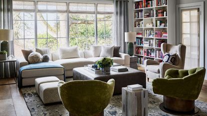 Living room with sofa, armchairs and coffee table centrally and bookcase behind