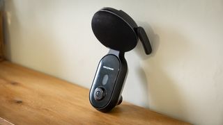Nextbase iQ dashcam on a wooden surface against a white wall