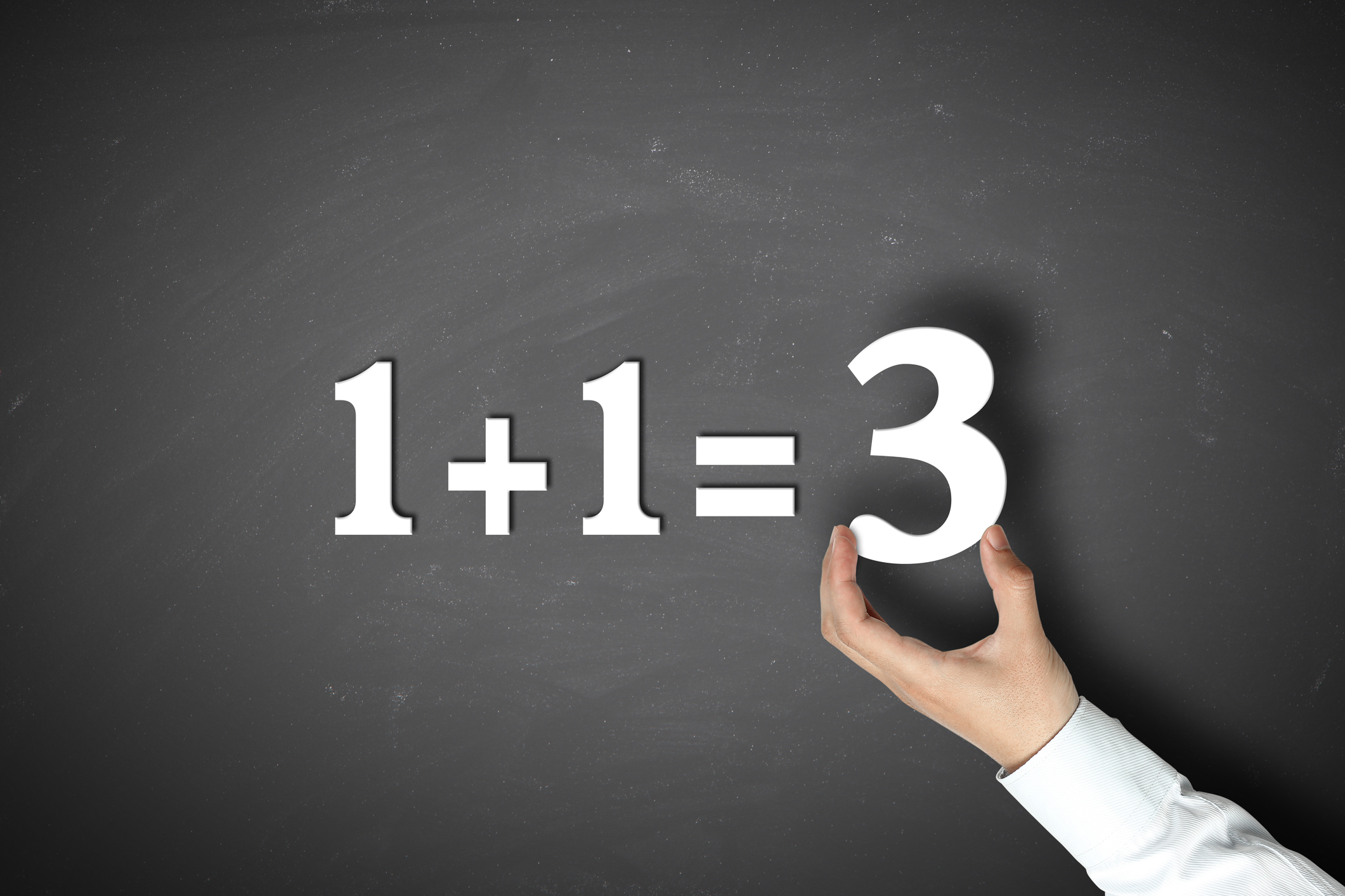 Business synergy concept 1+1=3 with Businessman holding on a blackboard.