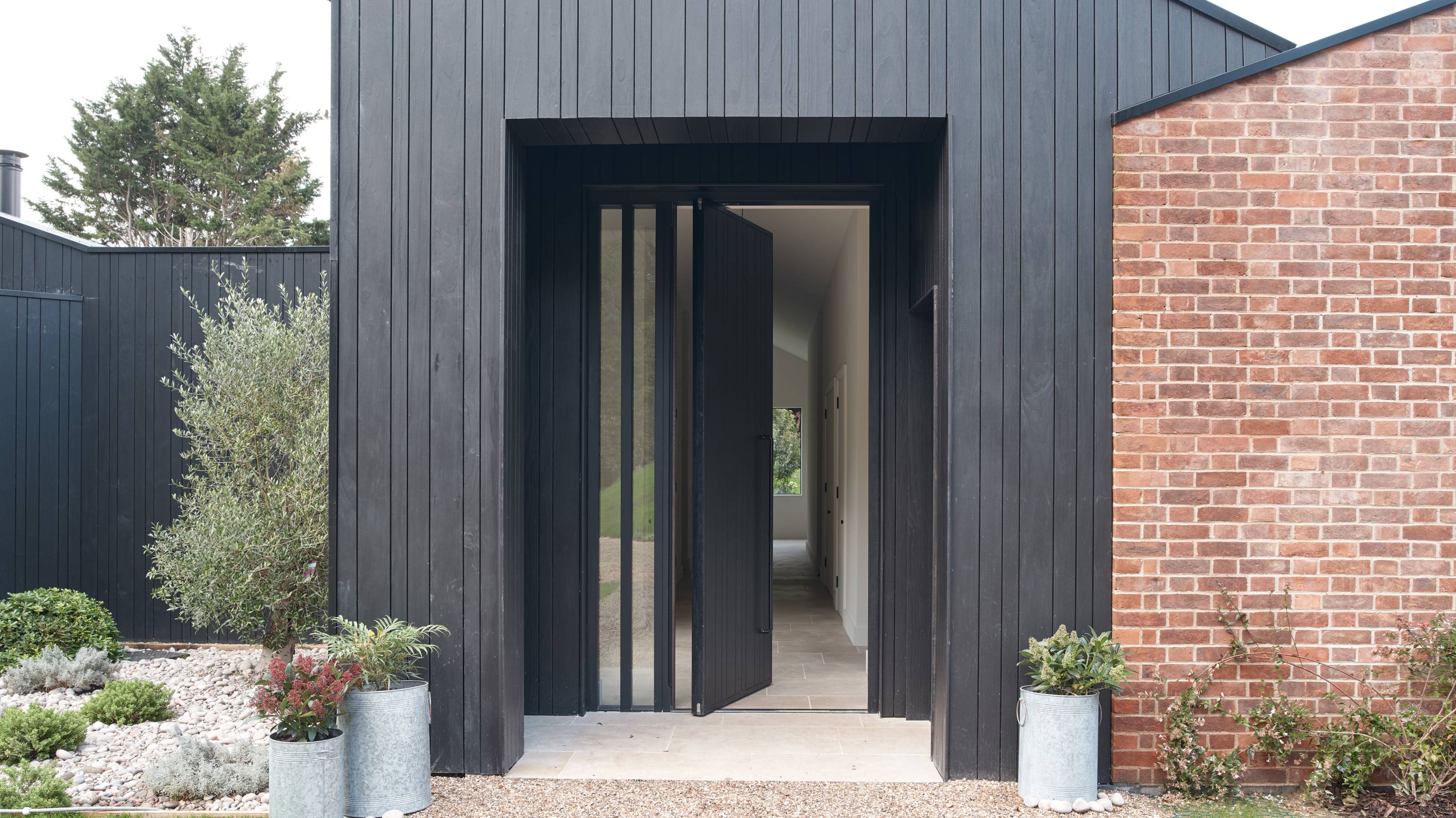 black wood and brick house with open pivot door
