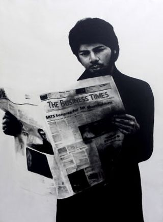 Black and white image of a man reading a copy of The Business Times newspaper